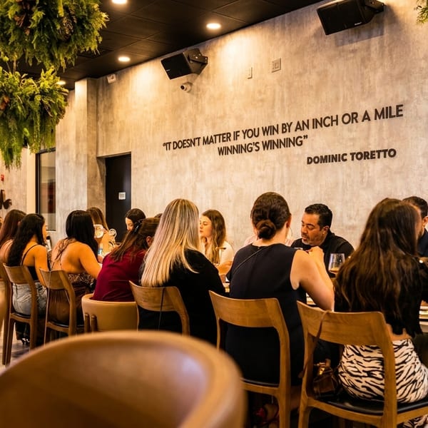 Diners seated at tables in a modern restaurant with hanging plants and a quote on the wall.