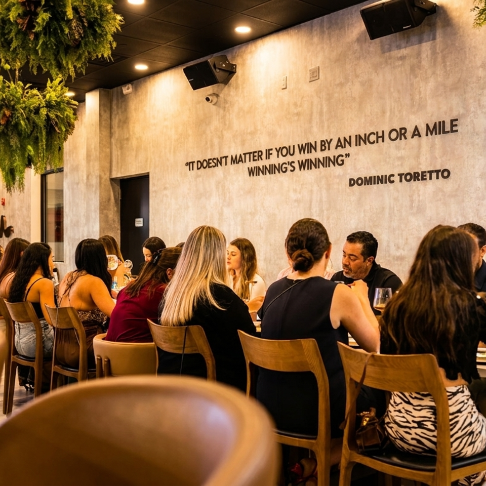Diners seated at tables in a modern restaurant with hanging plants and a quote on the wall.